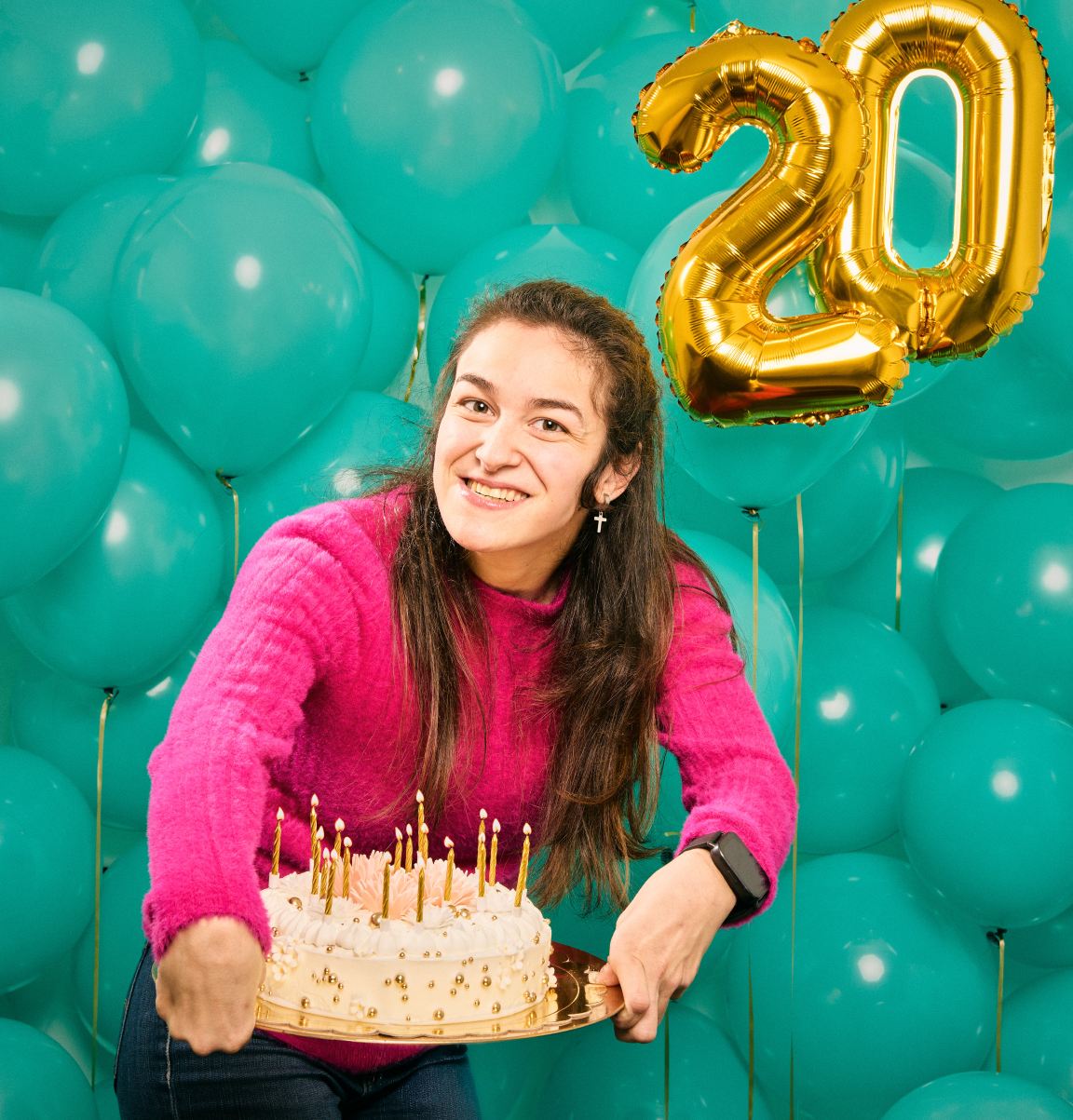Mujer con parálisis cerebral y discapacidad física sostiene una tarta ante globos del 20 aniversario