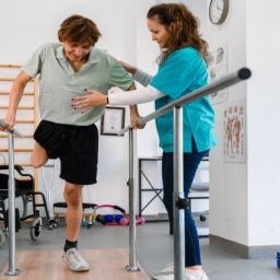 Persona con discapacidad realiza ejercicios de rehabilitación con apoyo de profesional sanitaria en un centro accesible