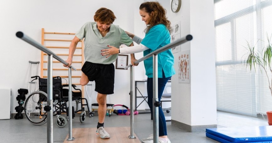 Persona con discapacidad realiza ejercicios de rehabilitación con apoyo de profesional sanitaria en un centro accesible