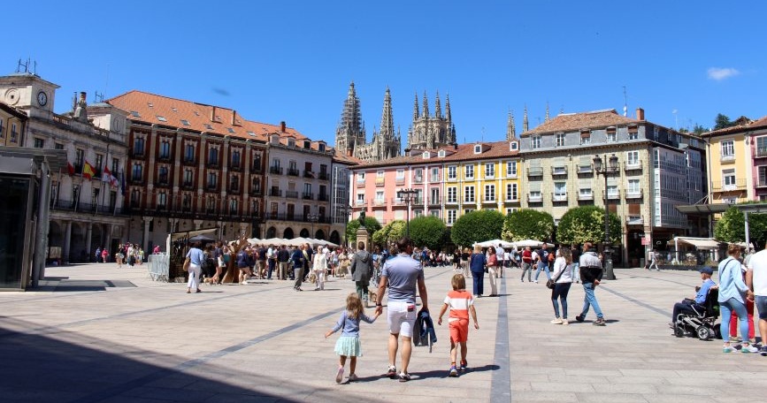 Personas paseando por una plaza de Burgos con la catedral al fondo en un día soleado