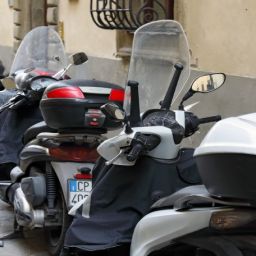 Motocicletas estacionadas en una acera urbana Varias motocicletas estacionadas en una acera, ocupando parte del espacio peatonal en una calle urbana.