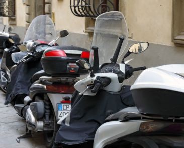Varias motocicletas estacionadas en una acera, ocupando parte del espacio peatonal en una calle urbana.