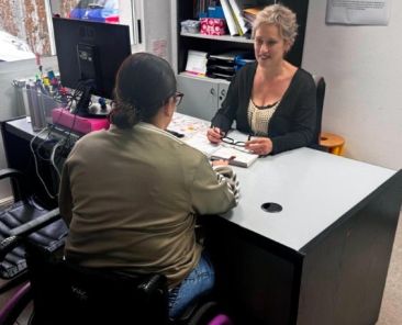 Atención individual a una participante del Servicio de Atención Especializada de COGAMI Profesional de COGAMI atiende a una mujer usuaria de silla de ruedas durante una sesión de orientación y acompañamiento individual.