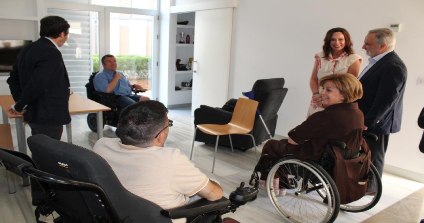 Personas usuarias de silla de ruedas y representantes institucionales visitan viviendas accesibles cedidas a COCEMFE Sevilla para un proyecto de vida independiente.
