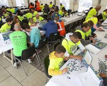 Participación y voluntariado en el Puzzle Cross de COCEMFE Castilla y León Personas participantes y voluntarias realizan una prueba de montaje de puzzles durante el Puzzle Cross organizado por COCEMFE Castilla y León.