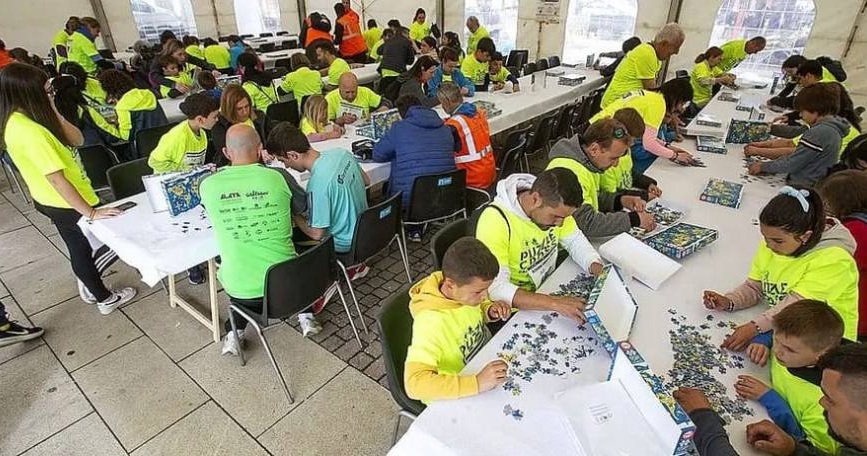 Personas participantes y voluntarias realizan una prueba de montaje de puzzles durante el Puzzle Cross organizado por COCEMFE Castilla y León.