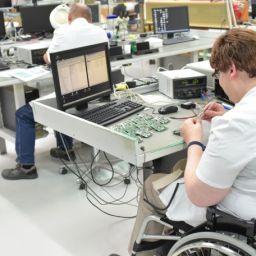 Persona con discapacidad en un entorno laboral inclusivo Persona usuaria de silla de ruedas trabaja en un laboratorio de electrónica como ejemplo de inclusión laboral de personas con discapacidad.