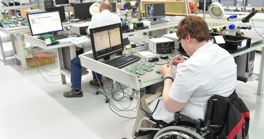 Persona usuaria de silla de ruedas trabaja en un laboratorio de electrónica como ejemplo de inclusión laboral de personas con discapacidad.
