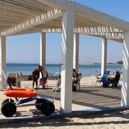 Punto accesible en una playa de Alicante Punto accesible de una playa de Alicante con pérgola, pasarela y silla anfibia para facilitar el acceso al baño de personas con discapacidad.
