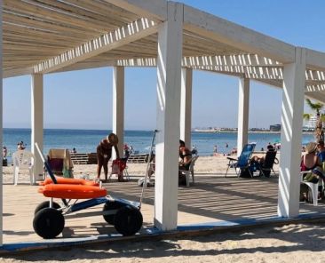 Punto accesible en una playa de Alicante Punto accesible de una playa de Alicante con pérgola, pasarela y silla anfibia para facilitar el acceso al baño de personas con discapacidad.