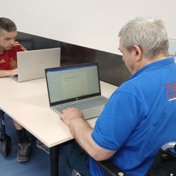 Dos personas usuarias de silla de ruedas utilizan ordenadores portátiles en las instalaciones de AGORA.
