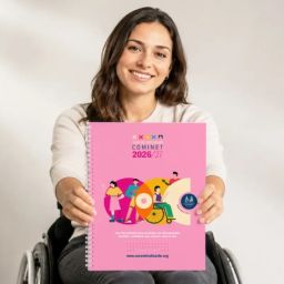 Guía de Recursos COMINET 2026/27 de COCEMFE Alicante Una mujer usuaria de silla de ruedas sostiene la Guía de Recursos COMINET 2026/27 de COCEMFE Alicante, una publicación gratuita con información sobre recursos, servicios y prestaciones de la provincia de Alicante.