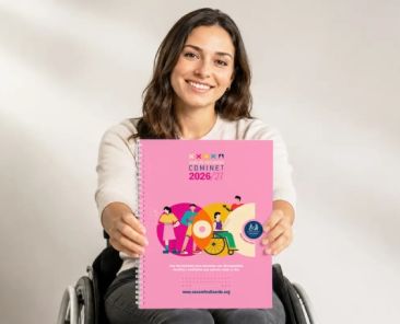 Guía de Recursos COMINET 2026/27 de COCEMFE Alicante Una mujer usuaria de silla de ruedas sostiene la Guía de Recursos COMINET 2026/27 de COCEMFE Alicante, una publicación gratuita con información sobre recursos, servicios y prestaciones de la provincia de Alicante.