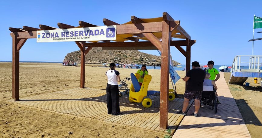 Zona reservada accesible con pasarela de madera y silla anfibia en una playa de Mazarrón.