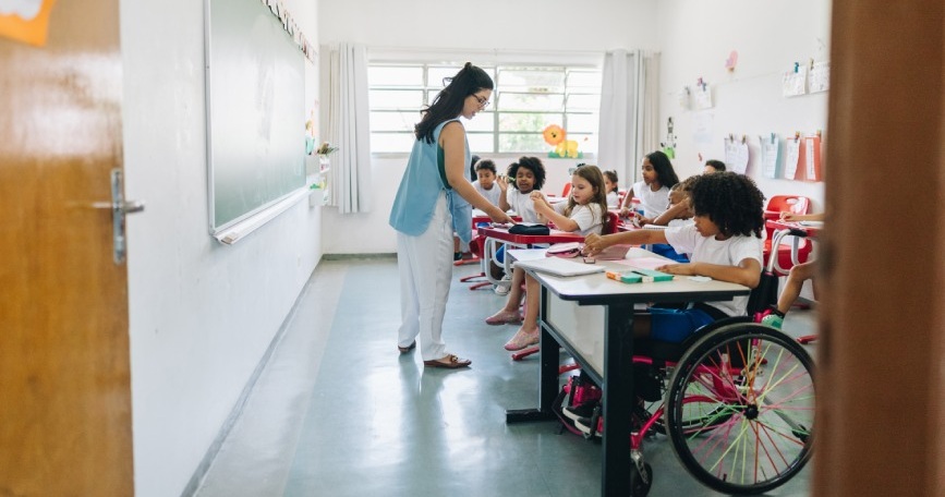 Docente y alumnado, incluida una alumna usuaria de silla de ruedas, participando en una actividad en el aula.
