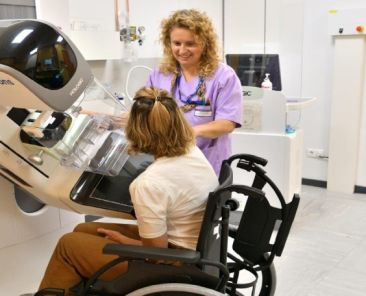 Mamografía a una mujer usuaria de silla de ruedas Mujer usuaria de silla de ruedas realizándose una mamografía con apoyo de una profesional sanitaria.
