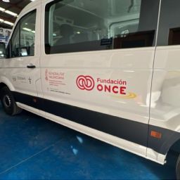 COCEMFE Castelló amplía su servicio de transporte adaptado con Fundación ONCE Furgoneta blanca de transporte adaptado de COCEMFE Castelló, con los logotipos de Fundación ONCE y Generalitat Valenciana, estacionada en una nave.