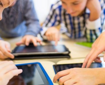 TIC y productos de apoyo para la educación inclusiva – COCEMFE Varios niños y niñas utilizan tabletas digitales alrededor de una mesa durante una actividad educativa.