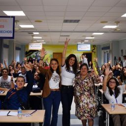 Participantes en una jornada de formación de FAMDIF en Totana Fotografía de grupo de participantes en una jornada de formación, con varias personas levantando los brazos y sonriendo en una sala con mesas y sillas. Algunas utilizan silla de ruedas.