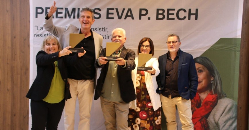 Cinco personas posan ante el cartel de los Premios Eva P. Bech durante la ceremonia de entrega en Badajoz. Tres muestran sus galardones.