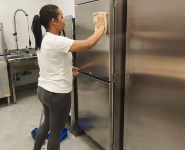 Mujer realizando una práctica de limpieza en una cocina profesional durante una formación de FEKOOR.