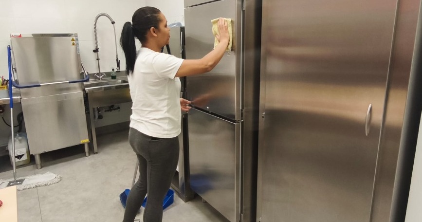 Mujer realizando una práctica de limpieza en una cocina profesional durante una formación de FEKOOR.